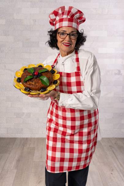 Daisy Yocasta Mallen in a chef's hat and apron holding a cake